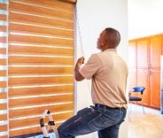 A male installling faux wood blinds