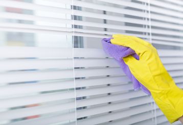 Person gently cleaning blinds with a microfiber cloth.