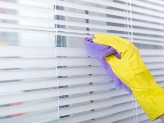 Person gently cleaning blinds with a microfiber cloth.