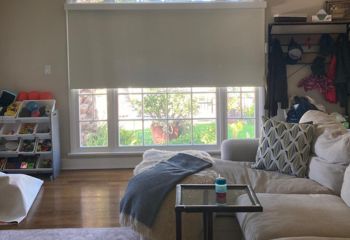 Custom roller shade partially open on a large arched living room window, showing natural light and modern design in an Oakland home