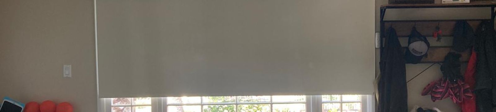 Custom roller shade partially open on a large arched living room window, showing natural light and modern design in an Oakland home.